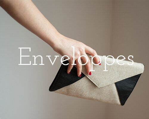 Enveloppes – voir la collection. Pochette enveloppe en lin et cuir noir tenue à la main