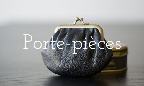 Porte-pièces – voir la collection. Porte-monnaie à fermoir en cuir noir posé près d’une boîte dorée