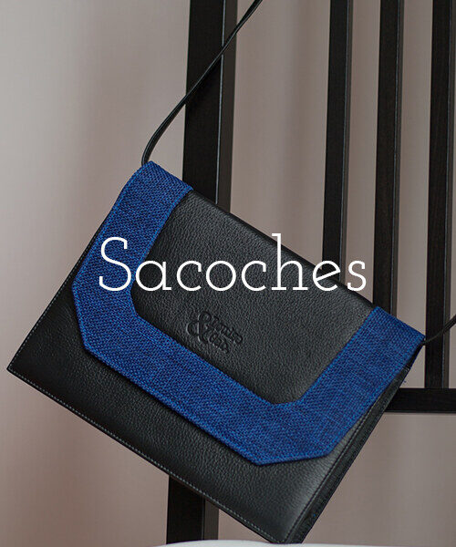 Sacoches – voir la collection. Sacoche en cuir noir et toile bleue suspendue à une chaise